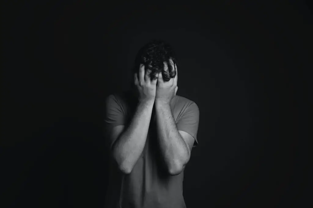 black and white photo of a man covering face with his hands
