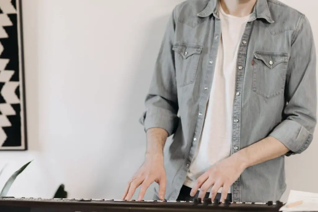 Man in grey buttoned up jacket playing the piano