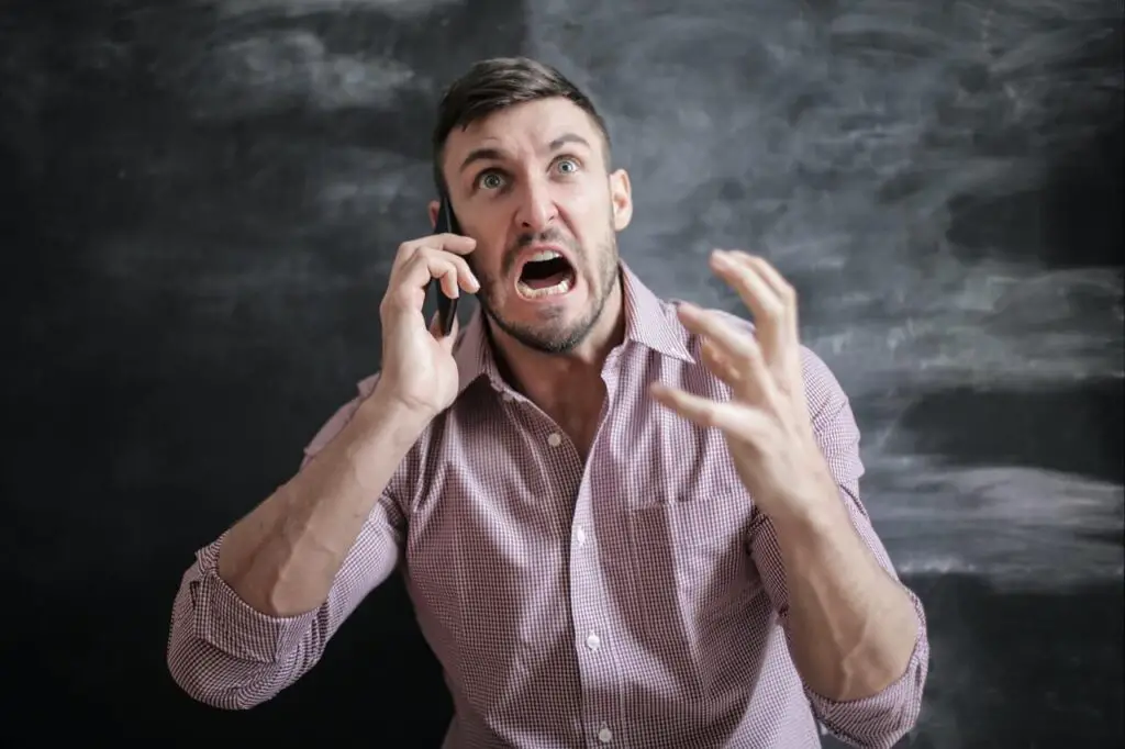 stressed man in pink shirt talking on the phone