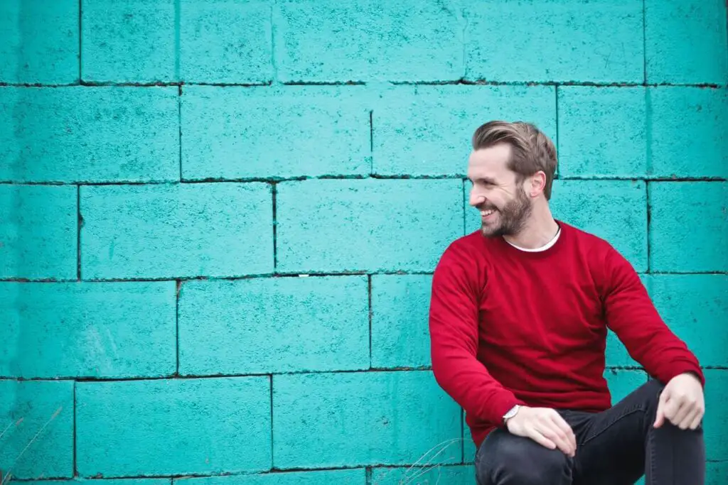 happy man wearing red sweatshirt and leaning on wall