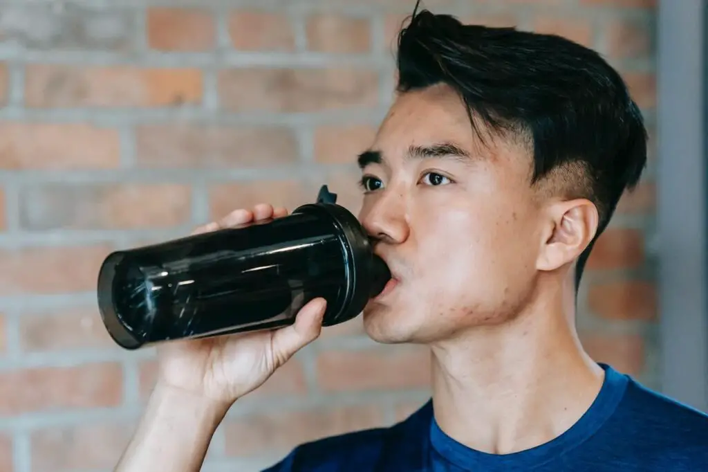 focused asian man drinking mass gainer 