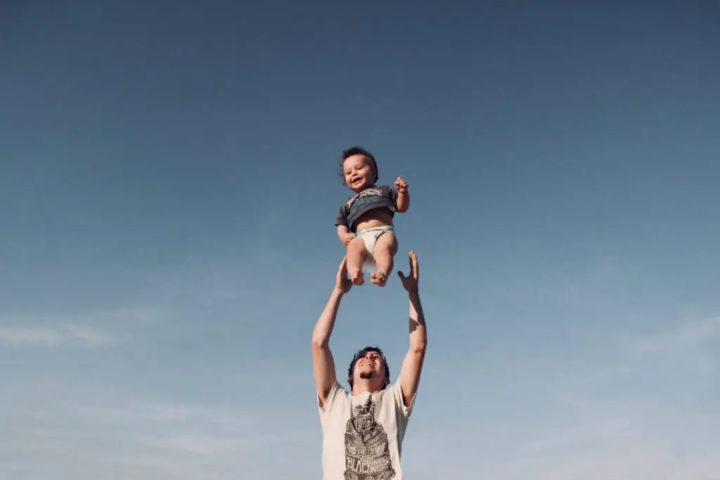 man raising baby in clear sky
