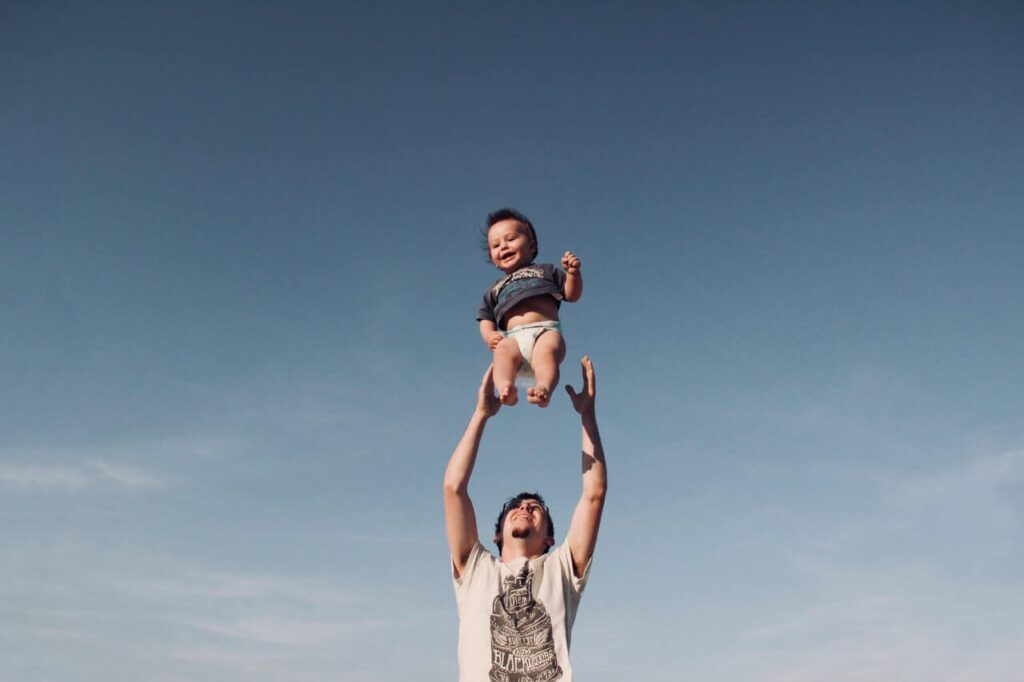 man raising baby in clear sky