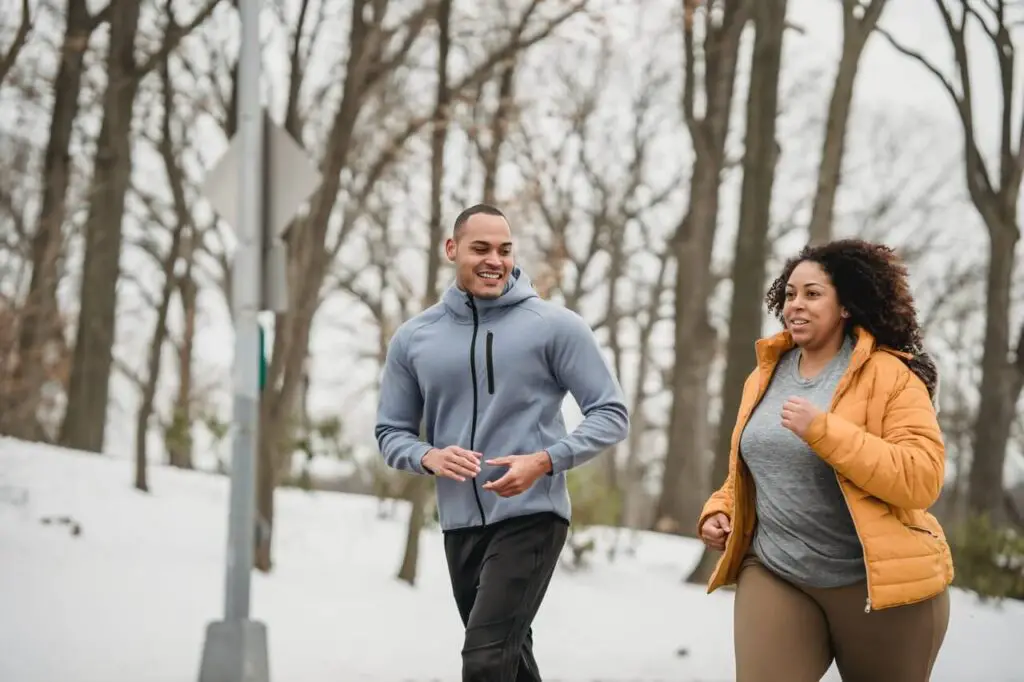 fit man and plump female running in a snowy park