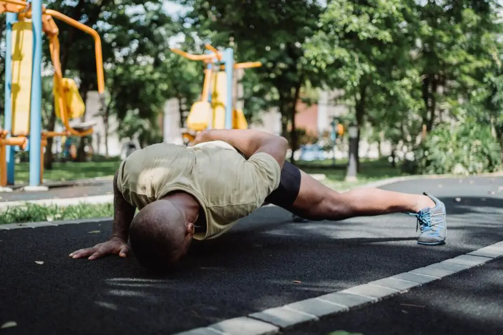 man doing one arm pushups on pavement