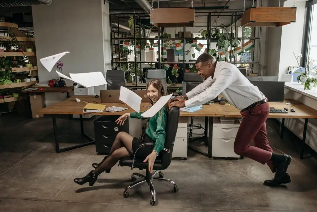 A man pushing a woman sitting on an office chair
