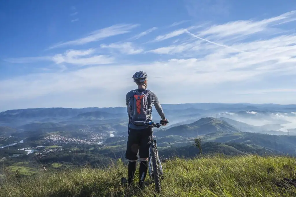 skinny guy checking mountain view near bicycle